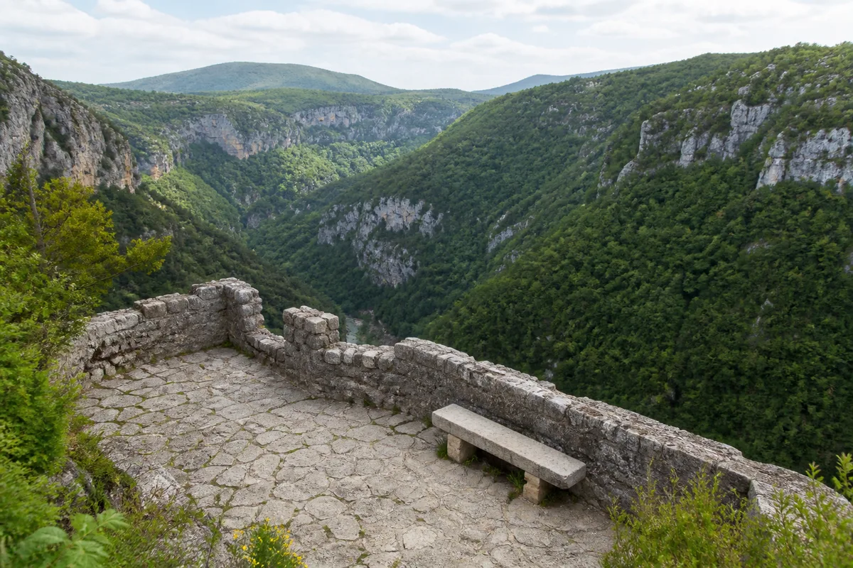 Terrasse de pierre en bord de falaise dominant le canyon boisé des gorges du Loup