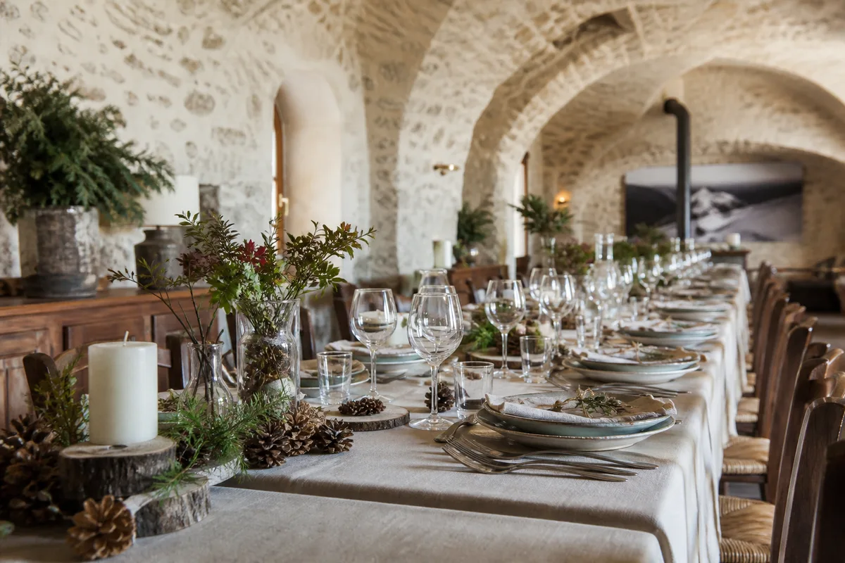 Grande table de banquet dressée dans une salle voûtée en pierre d&rsquo;une auberge de montagne